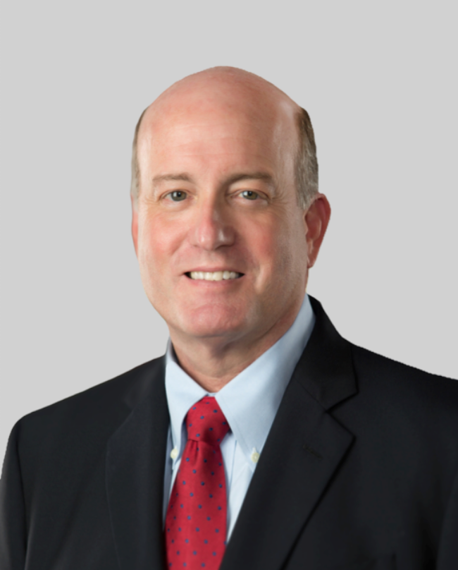 A bald man in a suit and tie is smiling for the camera