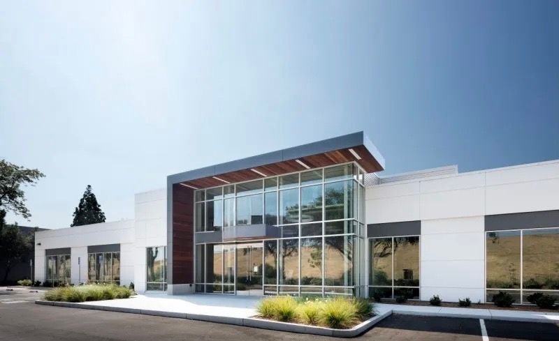 A large white building with a lot of windows and a parking lot in front of it.