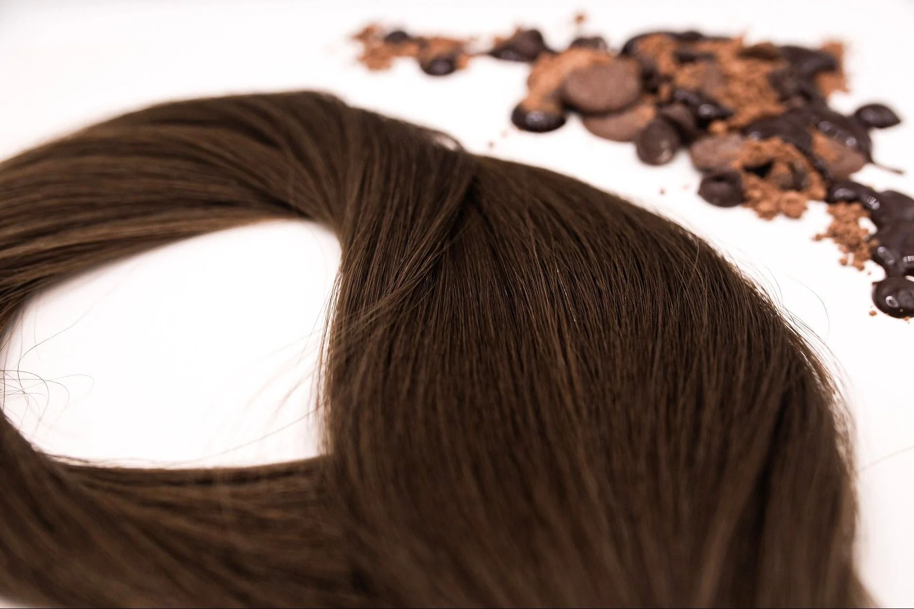 Brown hair strands with coffee beans on a white background