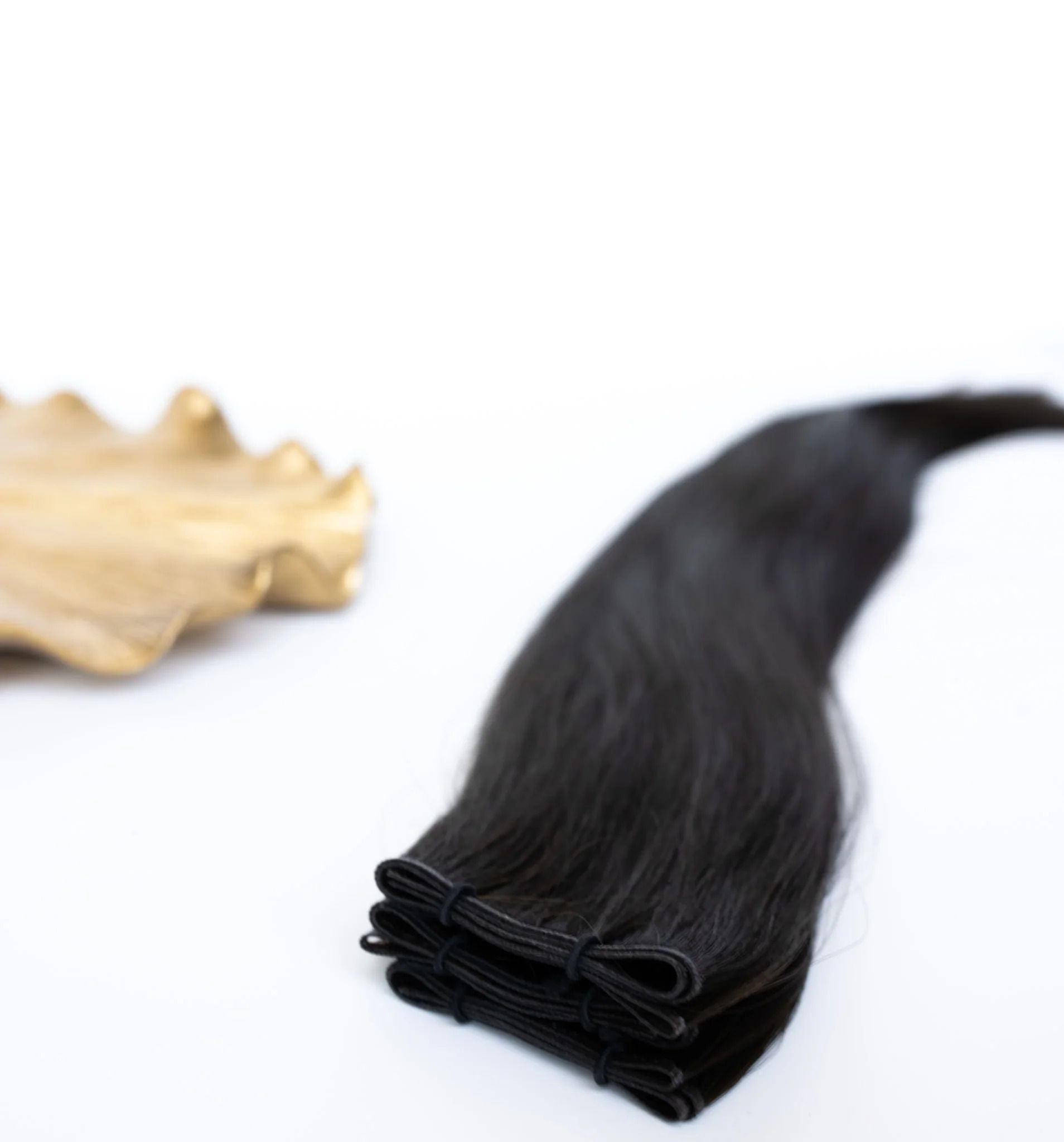 Black hair extension bundle beside a blonde sample on a white background