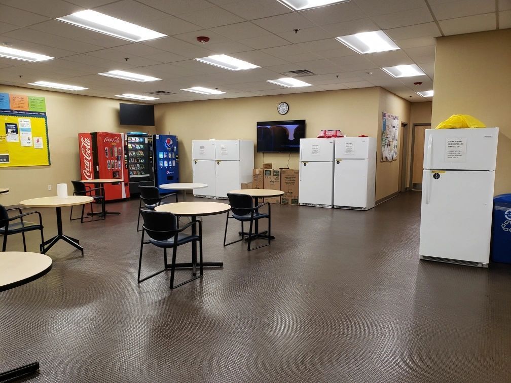 A break room with vending machines, tables, chairs, refrigerators, and a clock. A break room with vending machines, tables, chairs, refrigerators, and a clock.