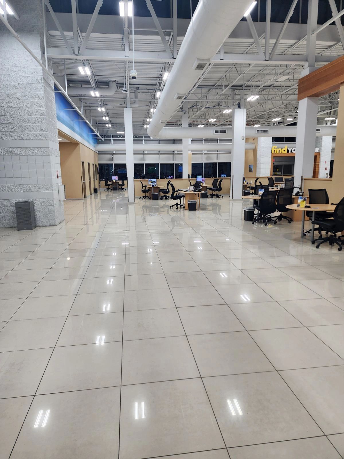 Large empty office with white tiled floor, desks, and overhead lighting. Large empty office with white tiled floor, desks, and overhead lighting.