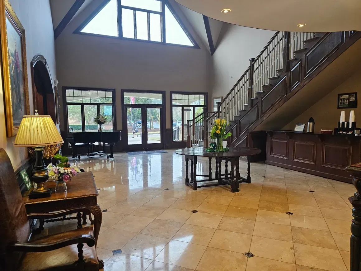 Grand foyer with marble floor, staircase, and a table with flowers. Grand foyer with marble floor, staircase, and a table with flowers.