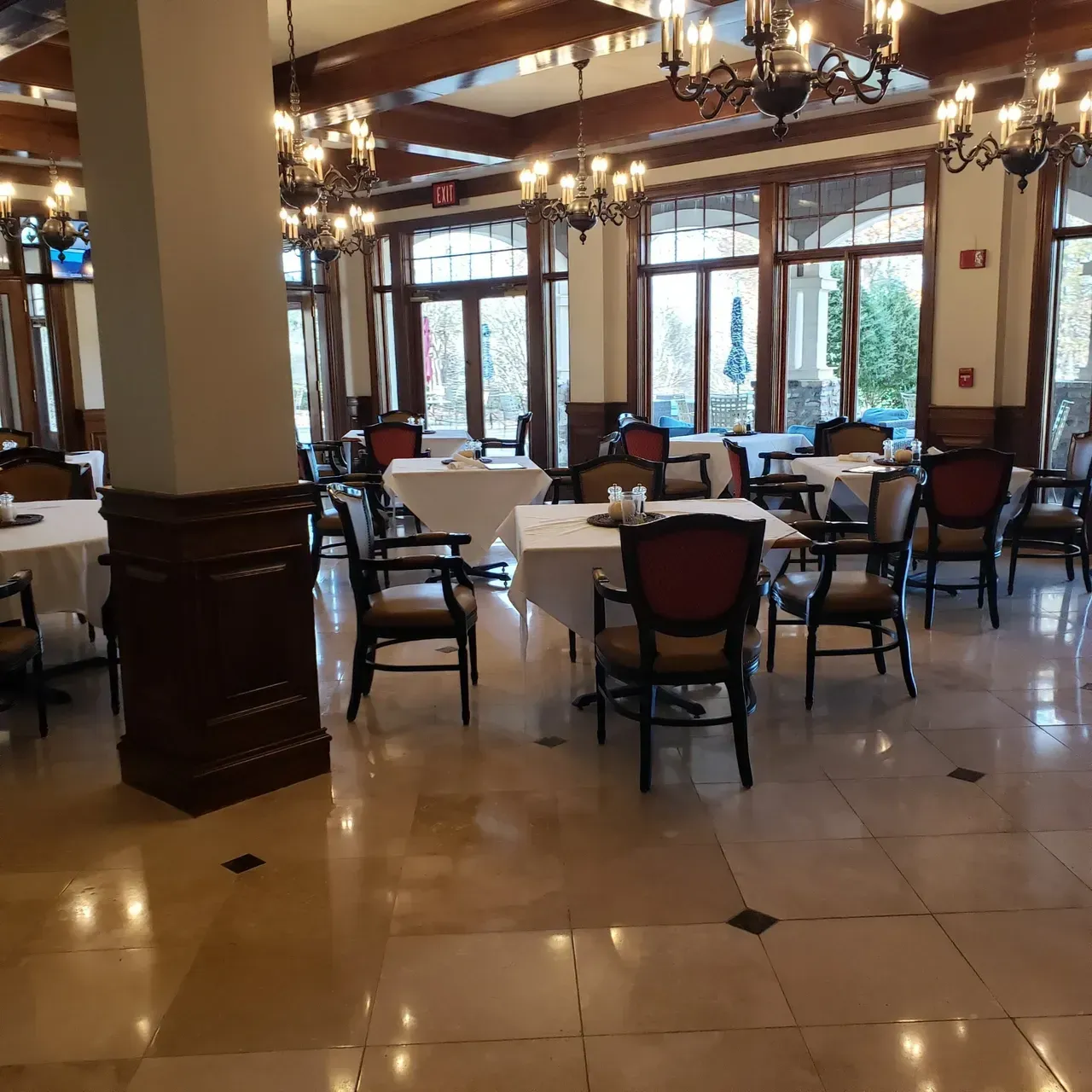 Dining room with tables set for service, chandeliers, large windows, and a marble floor. Dining room with tables set for service, chandeliers, large windows, and a marble floor.