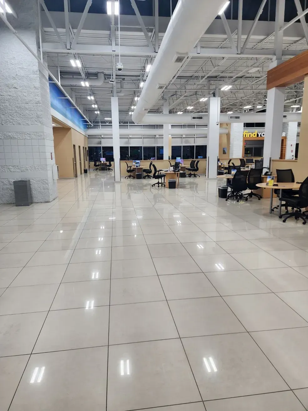 Bright, open office interior with tiled floors, desks, and overhead lighting. Bright, open office interior with tiled floors, desks, and overhead lighting.