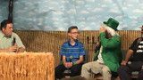 Three people seated on a stage with a woven hay backdrop and rustic farm props