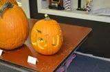 Two carved orange pumpkins on a table, one with a smiling face
