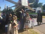 People posing by a vintage airplane float during an outdoor parade