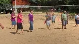 Children playing volleyball on a sandy court near a net outdoors