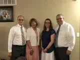 Four people standing indoors, smiling and posing for a group photo.