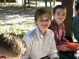 Three children sitting outdoors on a bench, smiling at the camera