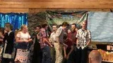 Group of people standing on a stage in front of colorful tropical painted backdrops