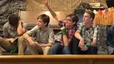 Five friends sitting together on a couch, laughing and talking in a cozy living room