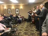 Musicians performing in a small room while an audience sits and listens