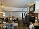 Living room gathering with people seated around a fireplace and large wall mirror