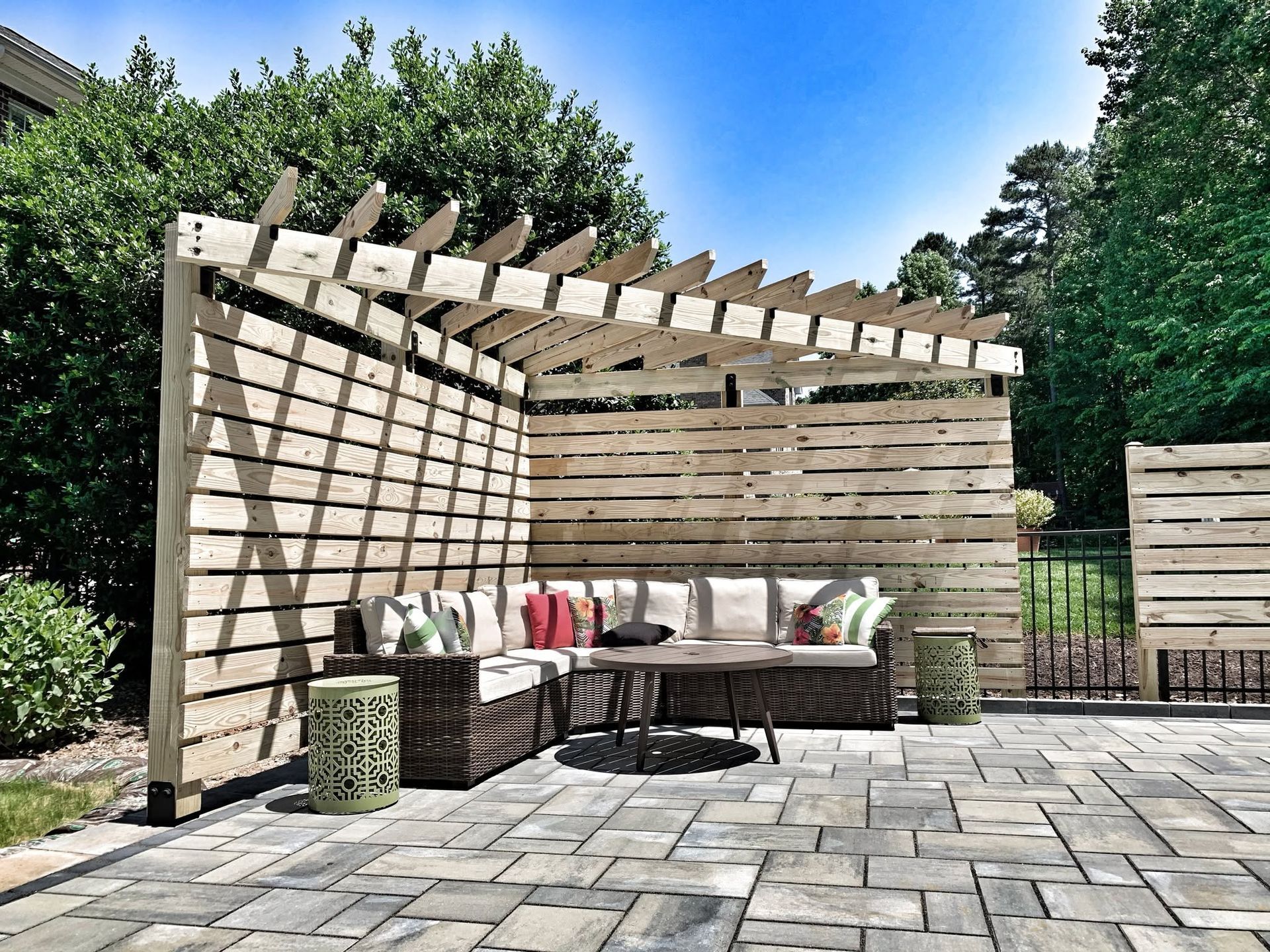 Modern patio with pergola, outdoor sofa, dining table, and stone paving in a sunny garden