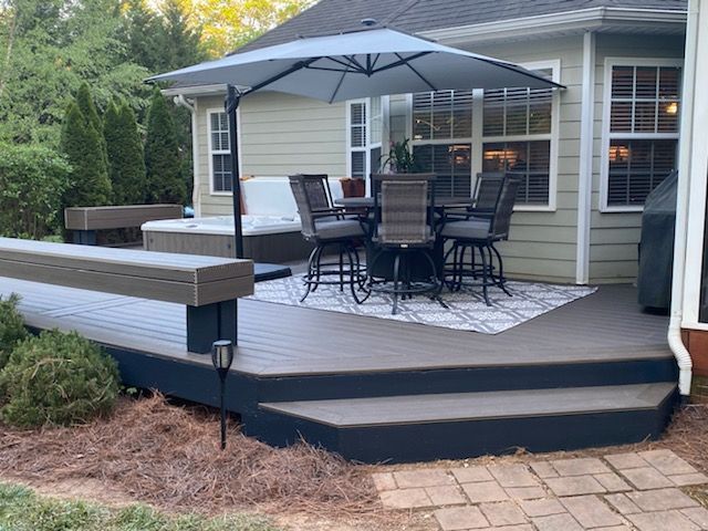 Back patio with outdoor dining set, umbrella, and deck steps beside a house