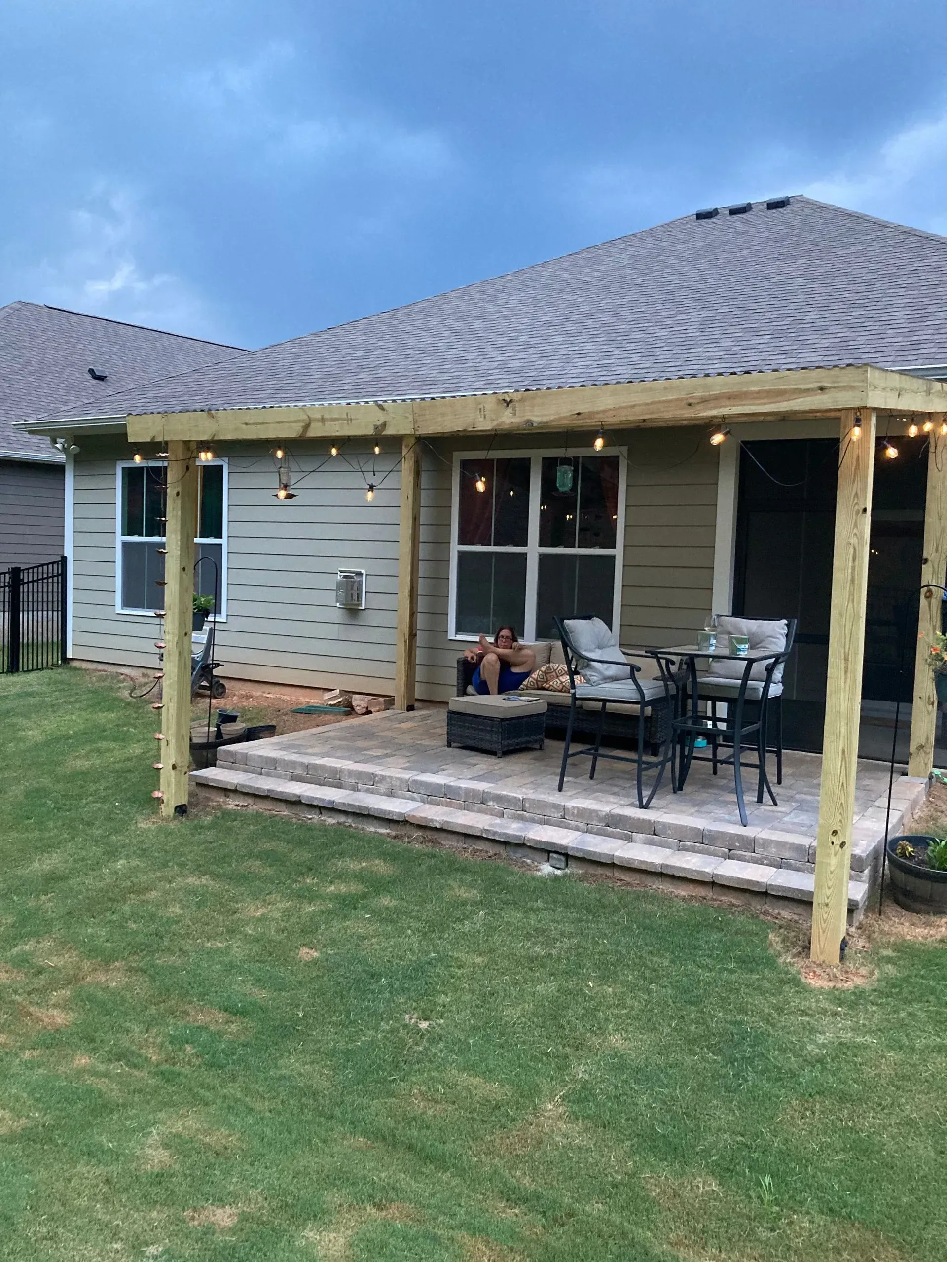 Back patio with chairs and potted plants beneath a covered porch of a beige house