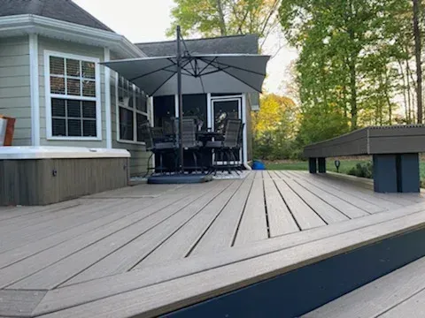 Back deck with gray composite boards, patio umbrella, outdoor seating, and a pool table