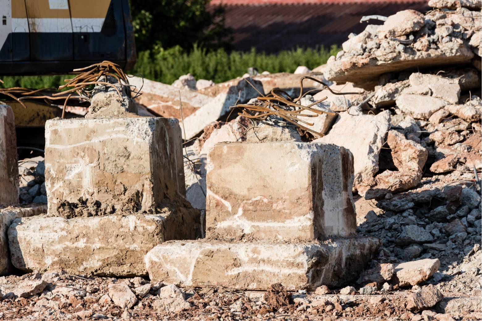 Concrete blocks and rubble piled at a demolition site with debris and exposed rebar.