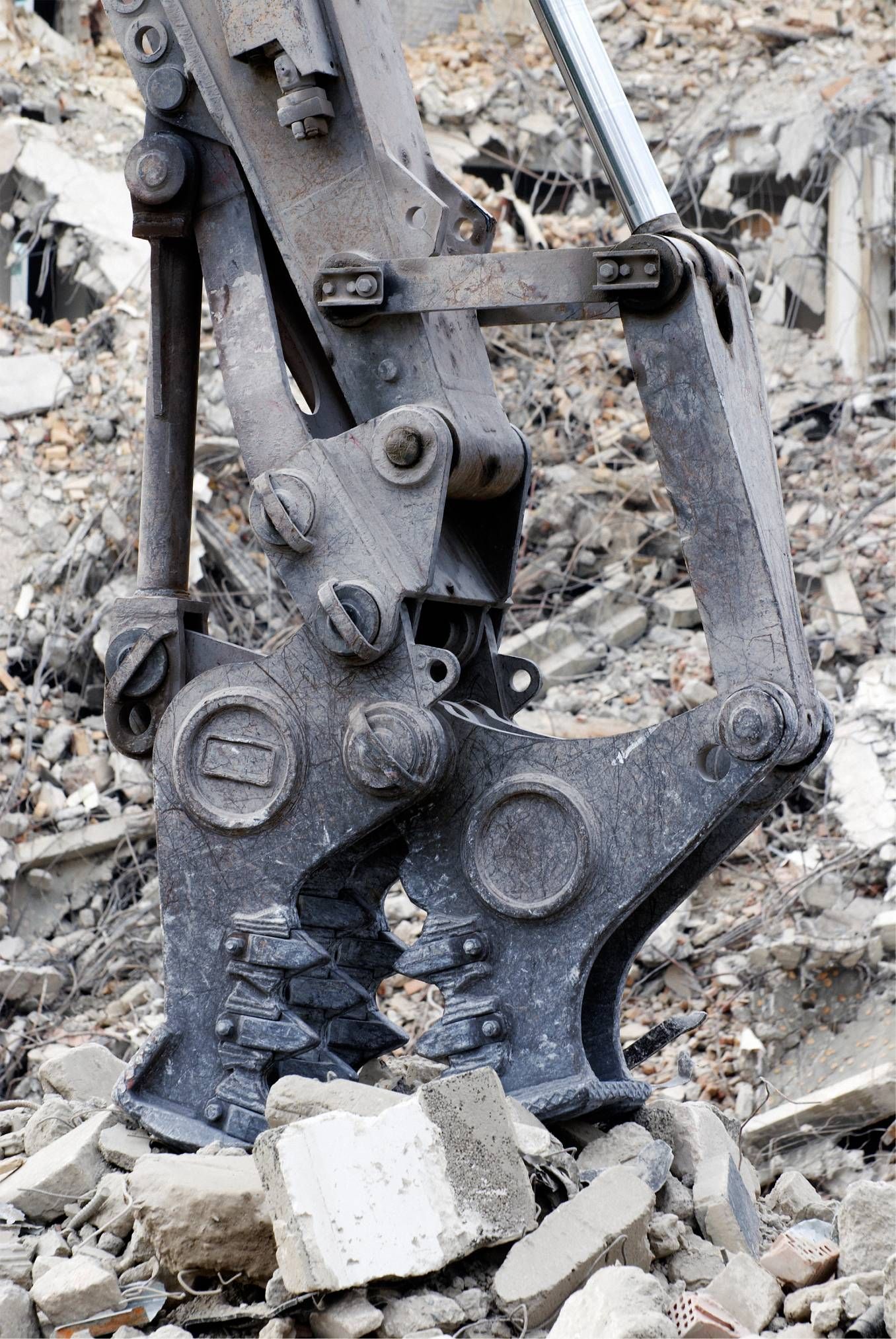 Excavator bucket and hydraulic arm breaking rubble in a demolition site