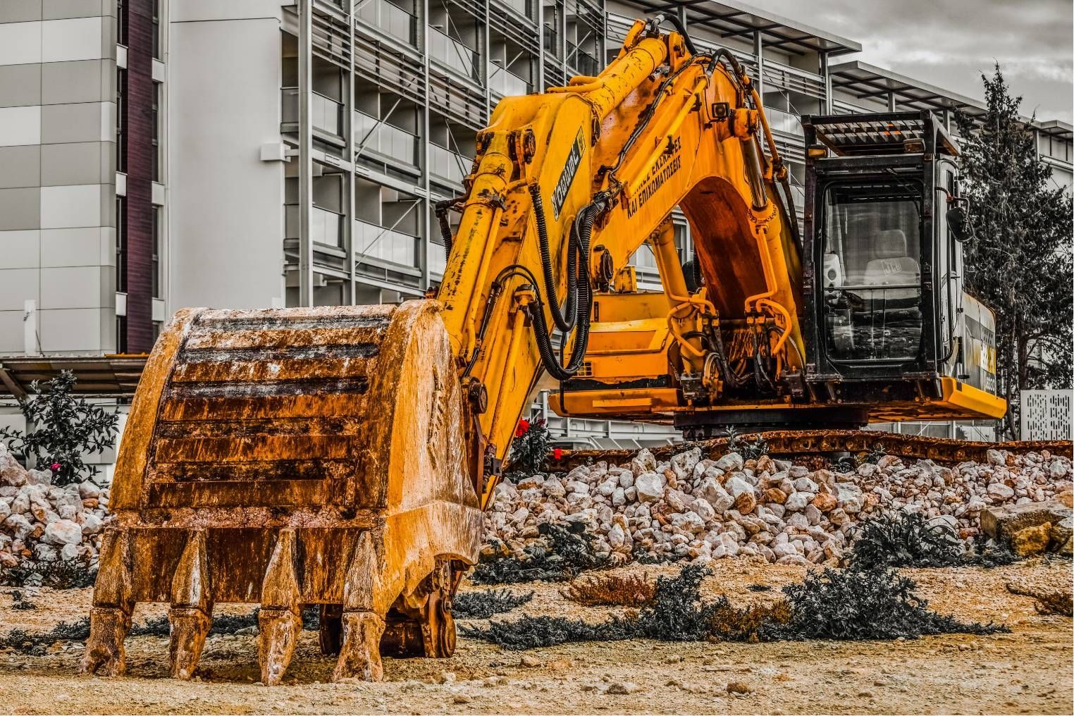 Orange excavator on a rubble pile at a construction site beside a building