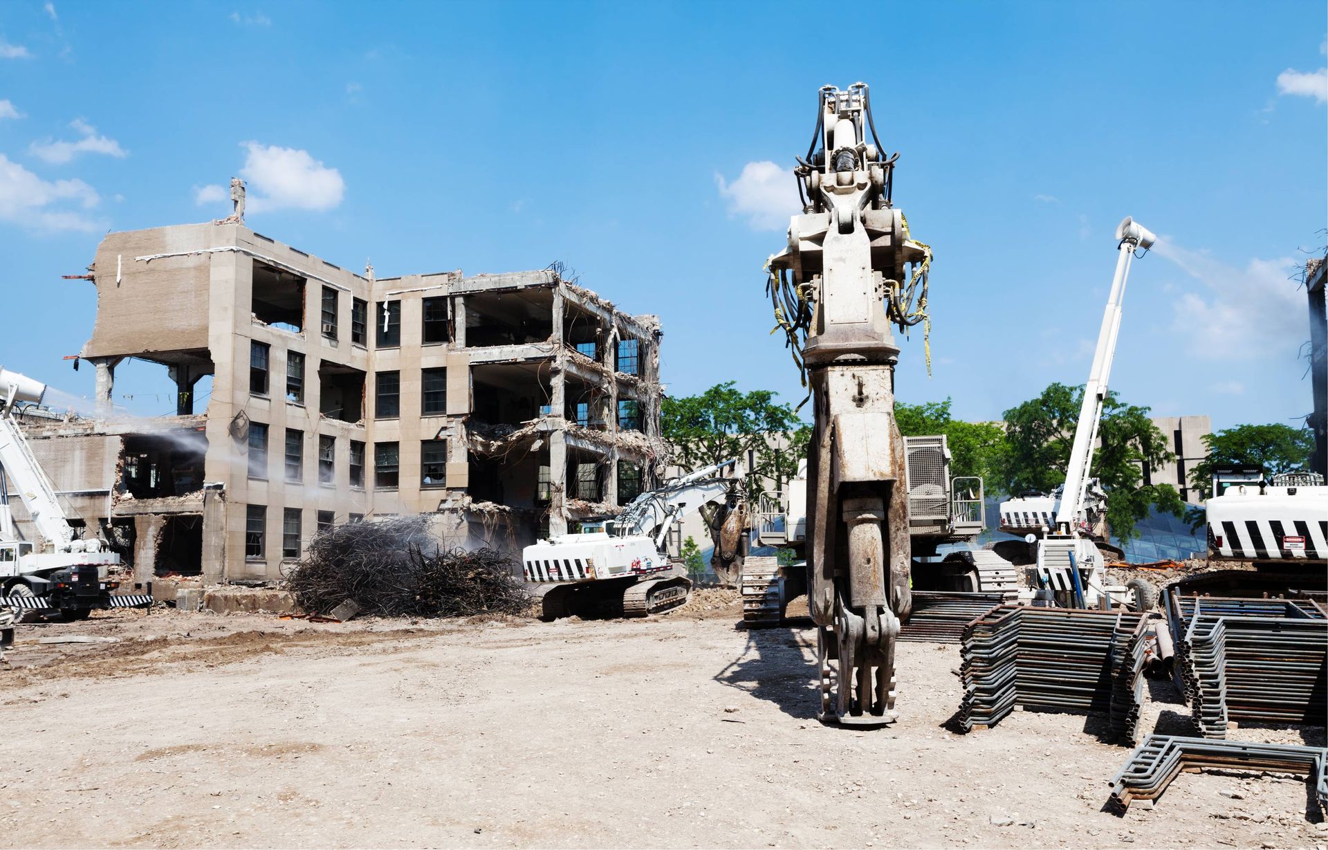 Demolition site with a partially destroyed building and excavator under a blue sky