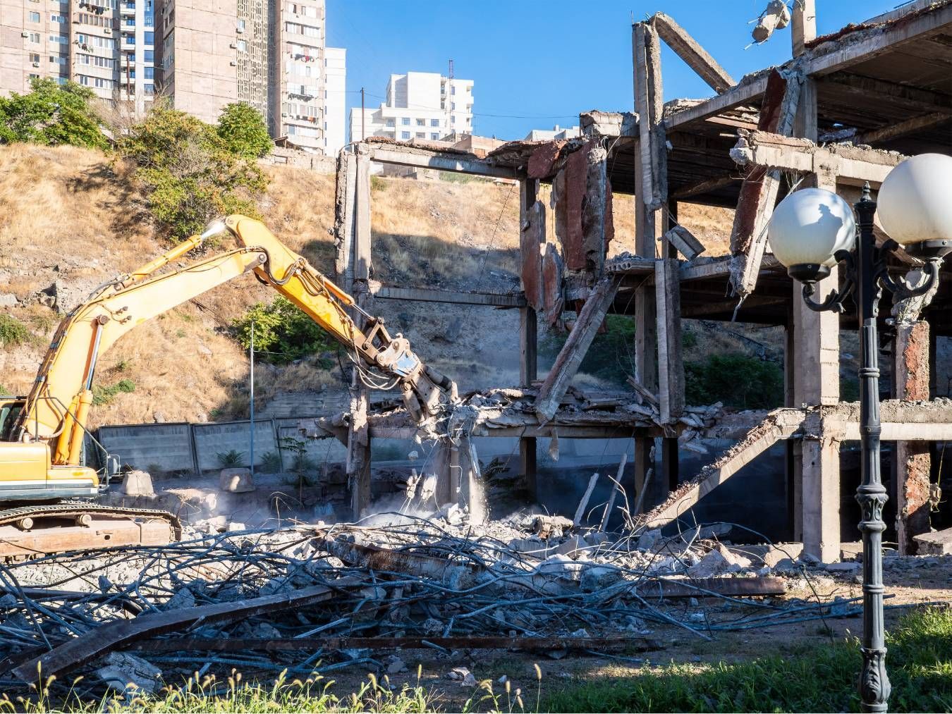 Burned-out construction site with a yellow excavator and damaged steel frame rubble