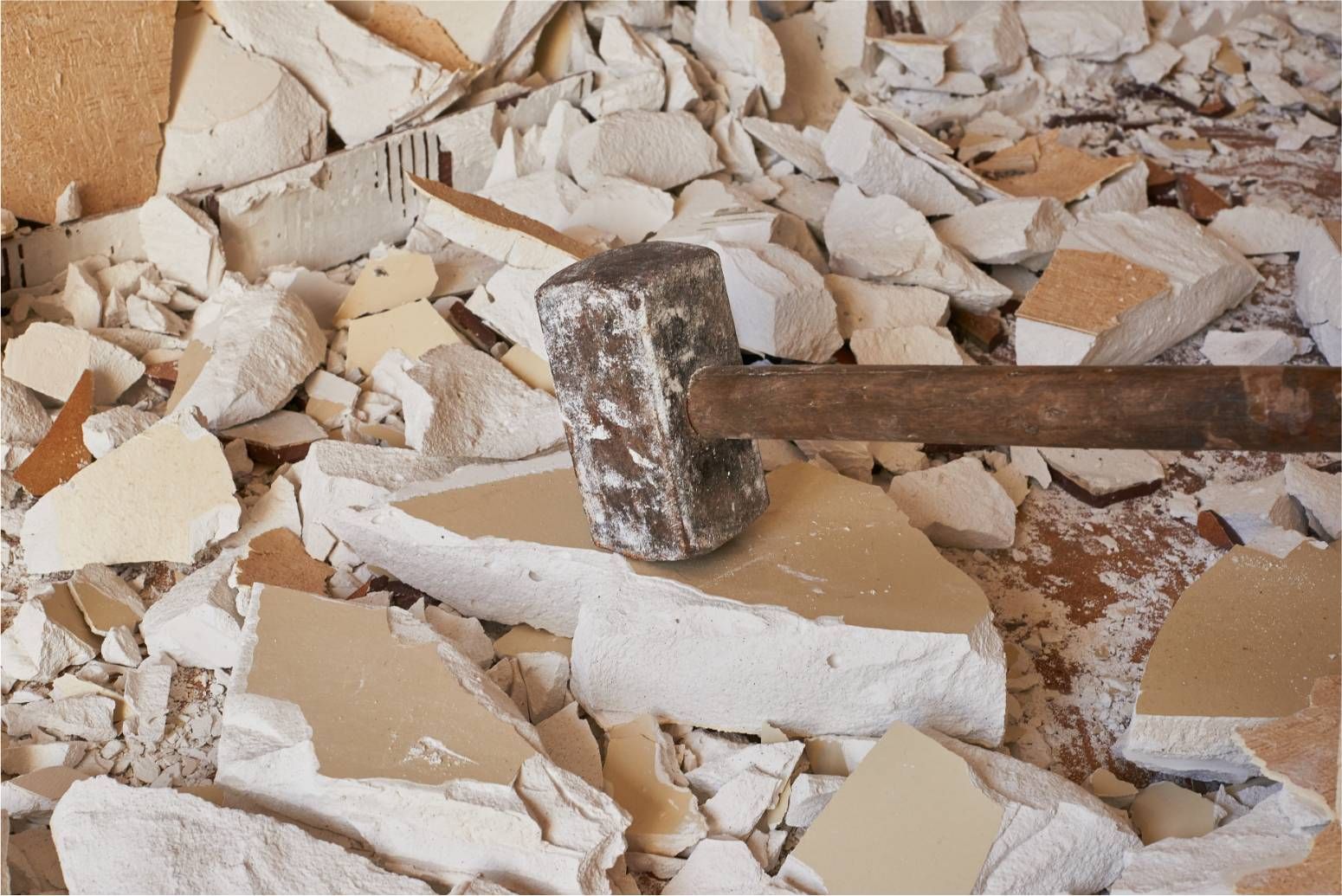 Hammer breaking plaster debris on a floor