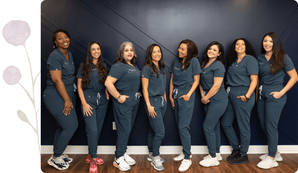 A group of women in scrubs are standing next to each other in front of a wall.