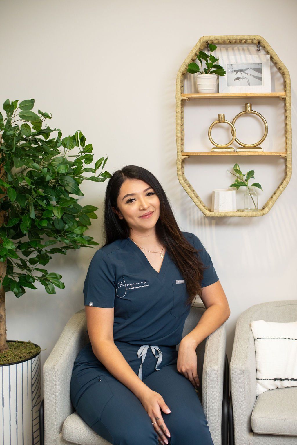 A woman in a scrub suit is sitting in a chair in a waiting room.