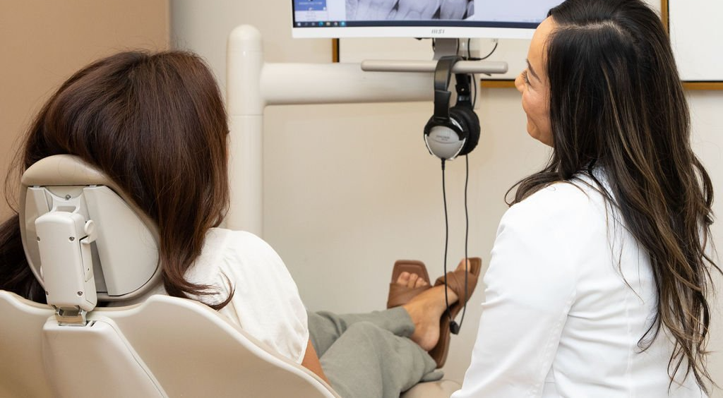 A woman is sitting in a dental chair talking to a dentist.
