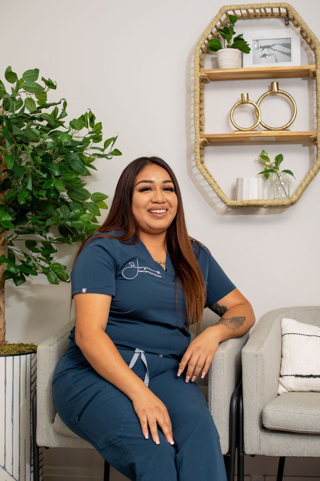 A woman in a scrub suit is sitting in a chair.