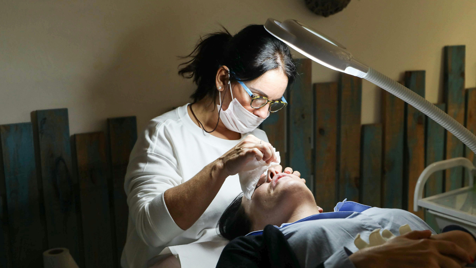 Dentist examining a patient’s mouth under a bright exam lamp in a clinic