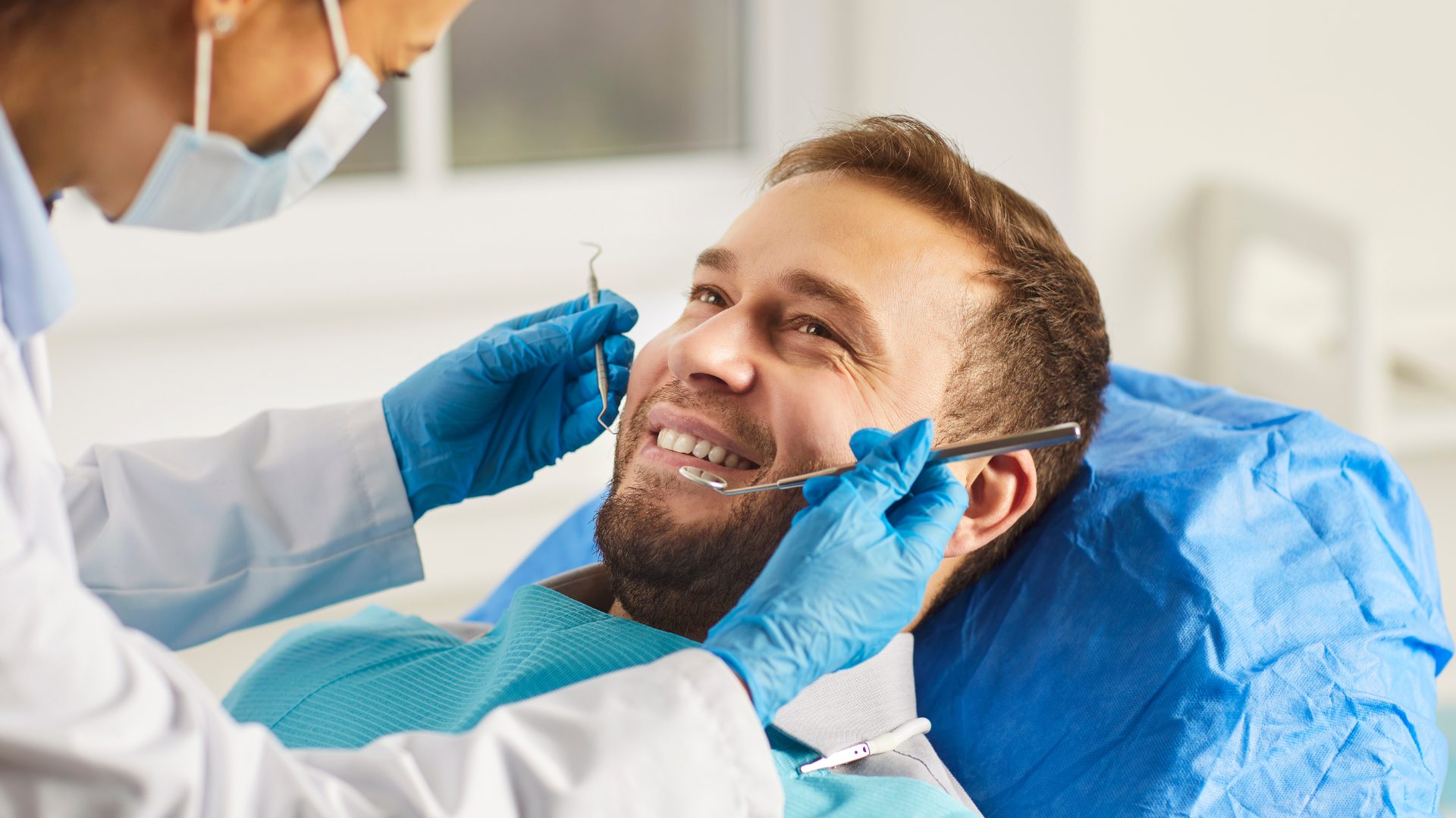 Dentist examining patient's teeth with dental instruments in a clinic setting.