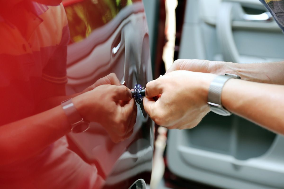 A person is opening a car door with a key.