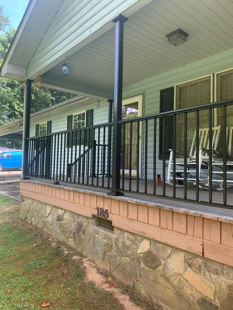 A white house with a custom porch and rocking chairs on it.
