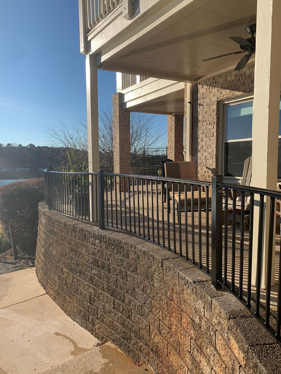 A house with a fence and a balcony overlooking a body of water.