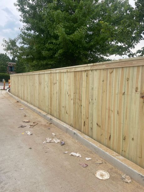 A wooden fence is being built on the side of a road.