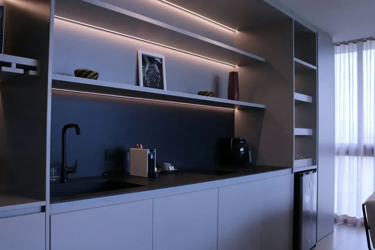 A kitchen with a sink , stove , and shelves.