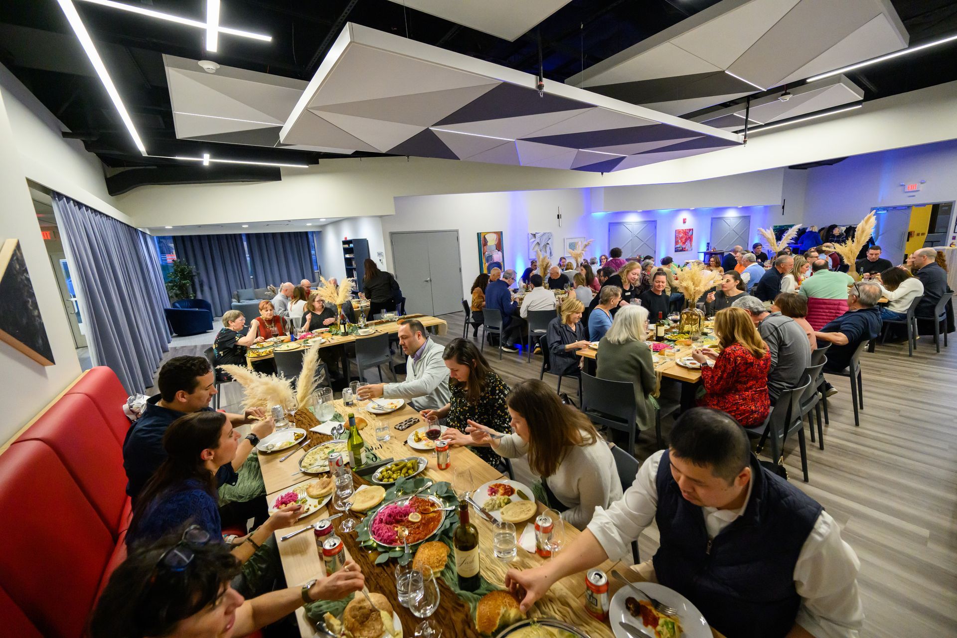 People seated at long tables, eating in a modern, well-lit dining area.