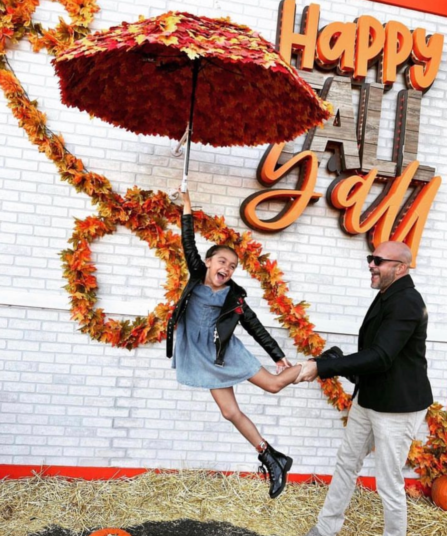Couple posing joyfully under red umbrella before autumn “Happy Fall” wall decor