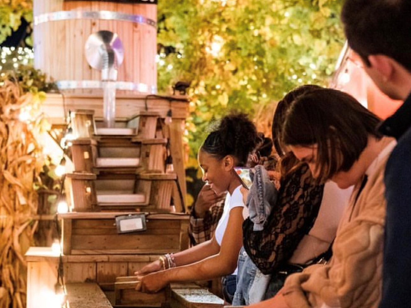 People seated at a wooden counter in a warm outdoor market or café setting