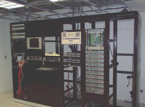 Server rack cabinet with electronics, monitors, and wiring in a data center room