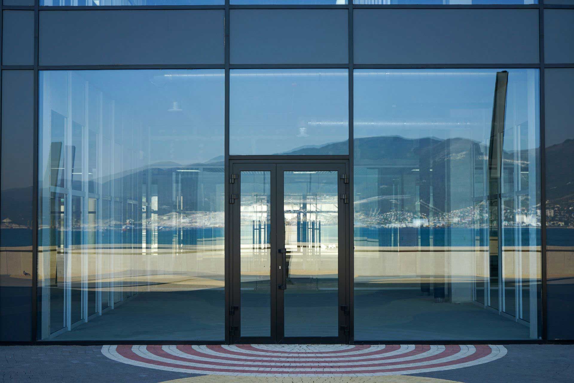 Glass building entrance with mirrored reflection of mountains and water. Glass building entrance with mirrored reflection of mountains and water.