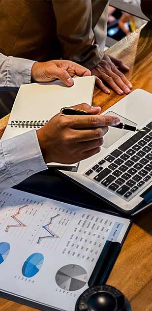 A person is sitting at a table with a laptop and a notebook.
