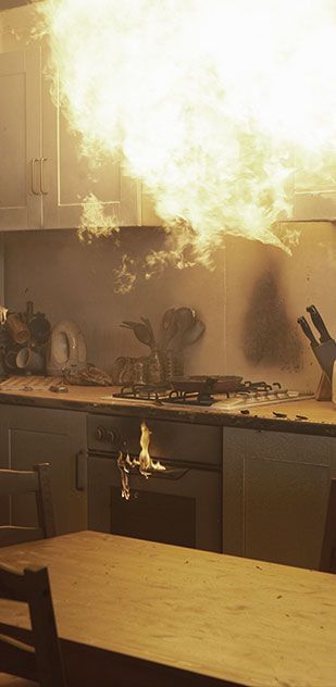 A kitchen with a fire coming out of the stove.