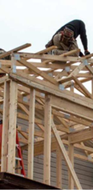 Two men are working on the roof of a house under construction.