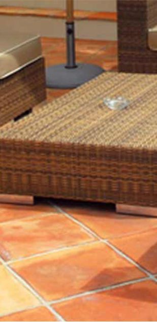 A wicker table is sitting on a tiled floor next to a chair.