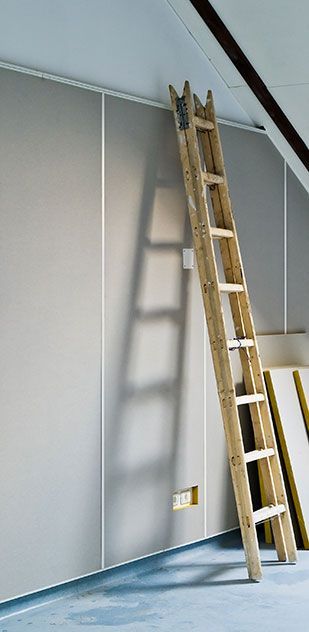 A wooden ladder is leaning against a wall in a room.